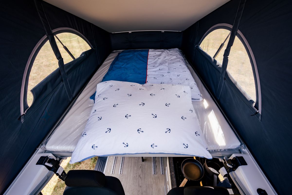 Doppelbett im geöffneten VW-Aufstelldach mit drei Fenstern