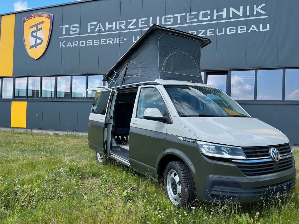 VW T6.1 in zweifarbig Ascotgrau/Grün, Ansicht schräg von vorn vor der Halle in Weida